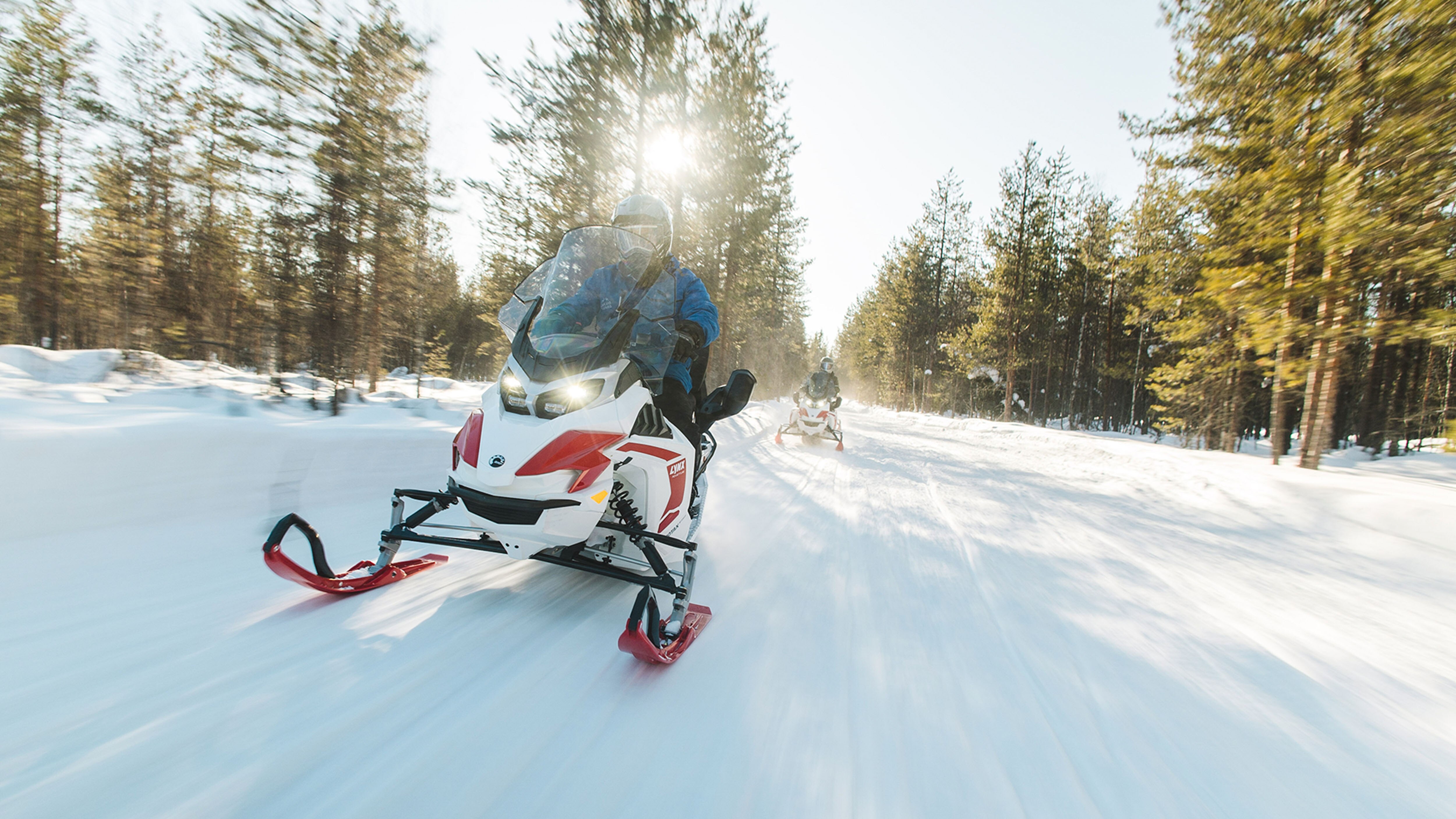 Two Lynx Adventure Electric snowmobiles riding on groomed trail