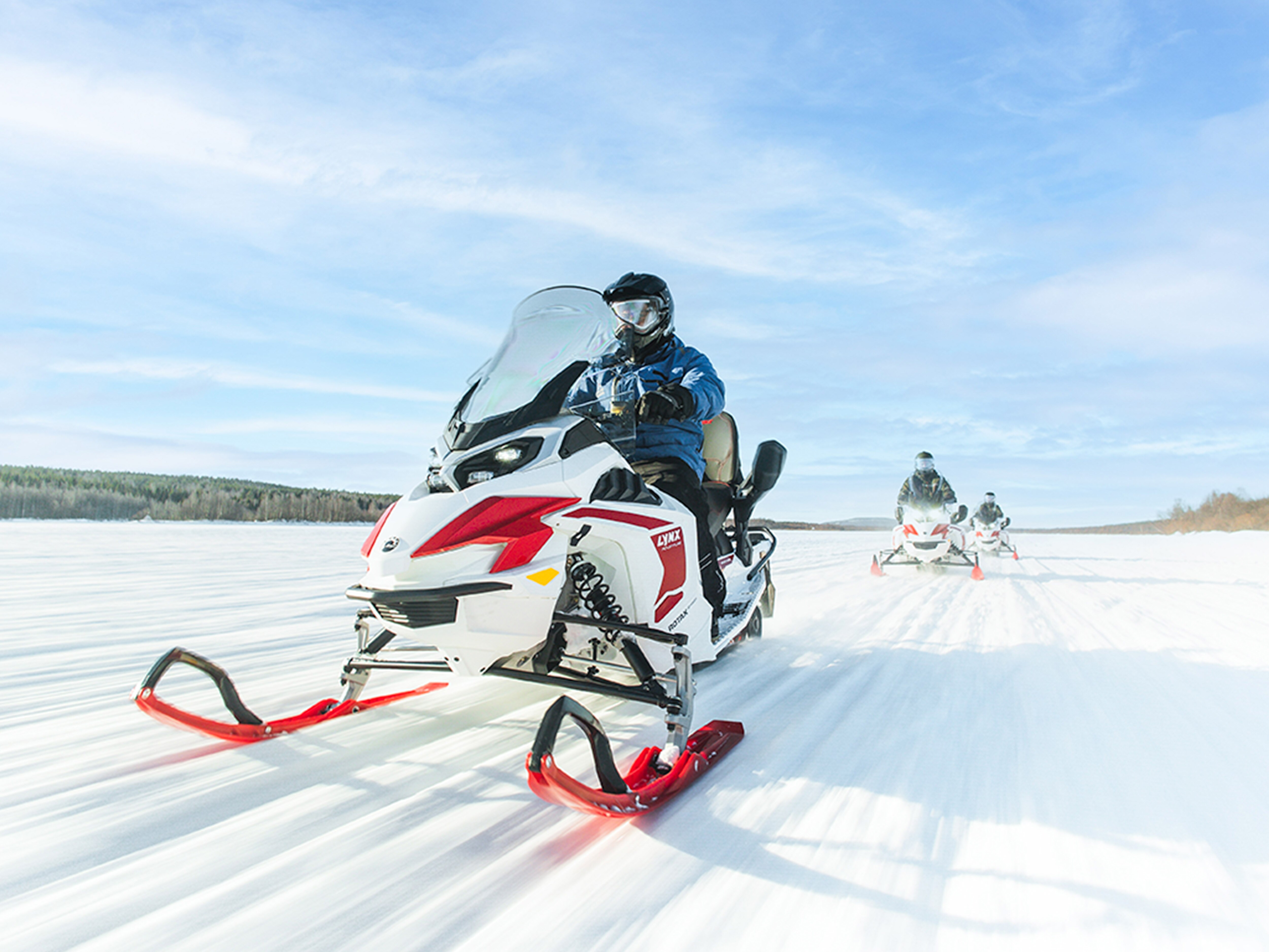 Three Lynx Adventure Electric snowmobiles riding on the lake ice