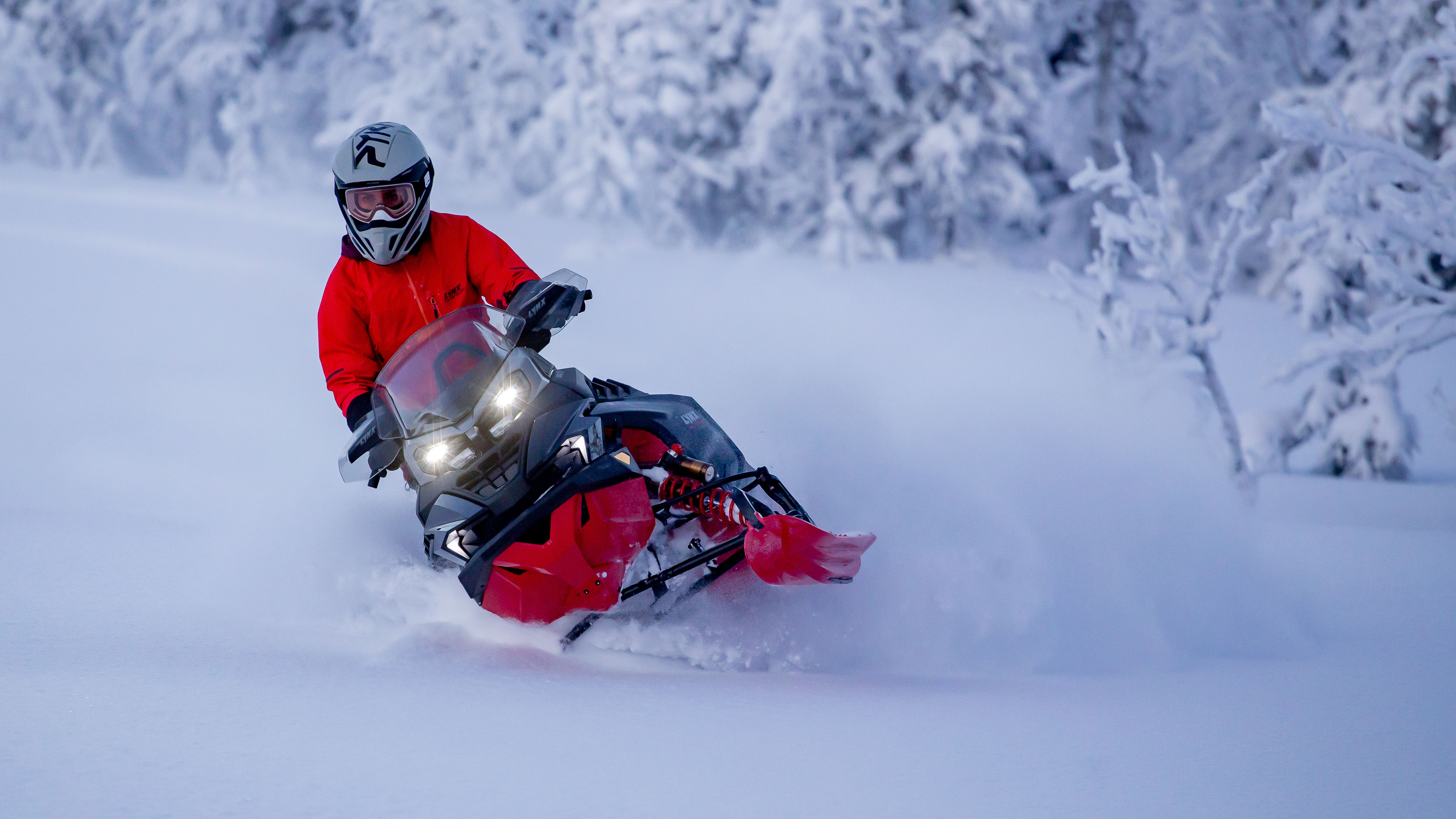 Snowmobiler on the 2026 Lynx Brutal snowmobile riding through the forest in deep snow.