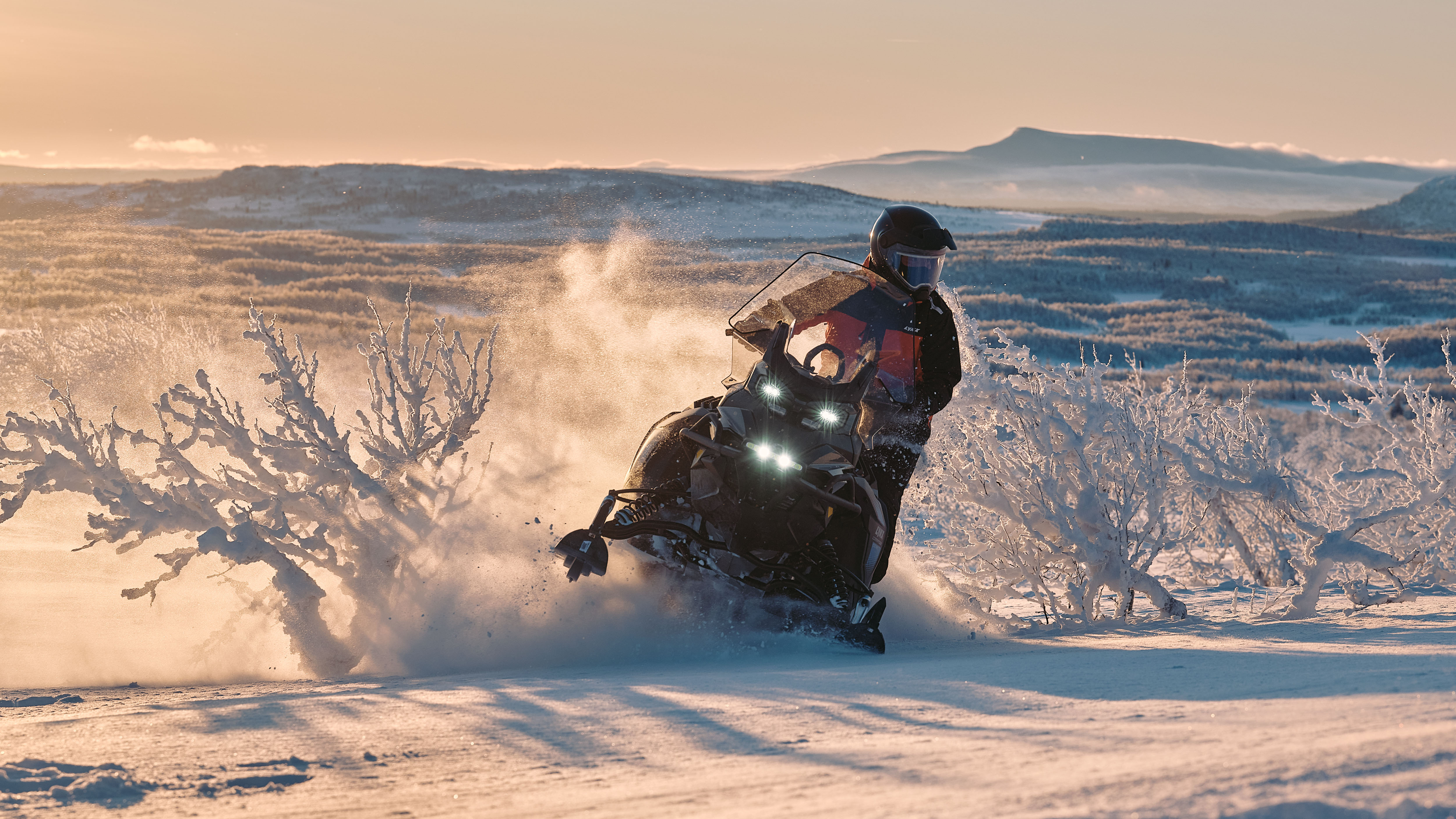 Kaksi Lynx Xterrain RE 2025 -moottorikelkkaa ajamassa reitillä auringonnousussa