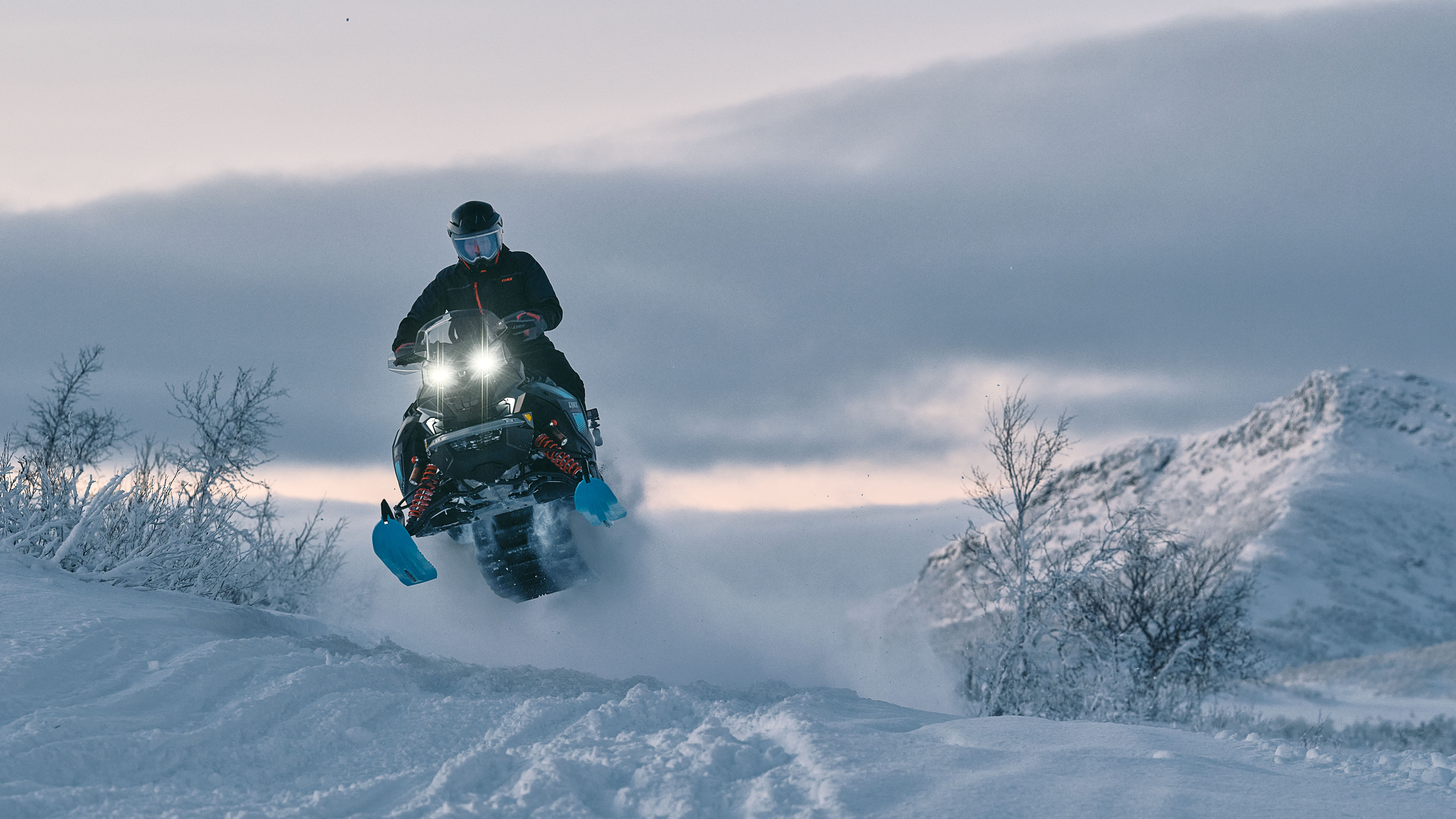 Snowmobiler on the 2026 Lynx Commander snowmobile flying over a deep snow trail in the forest. 