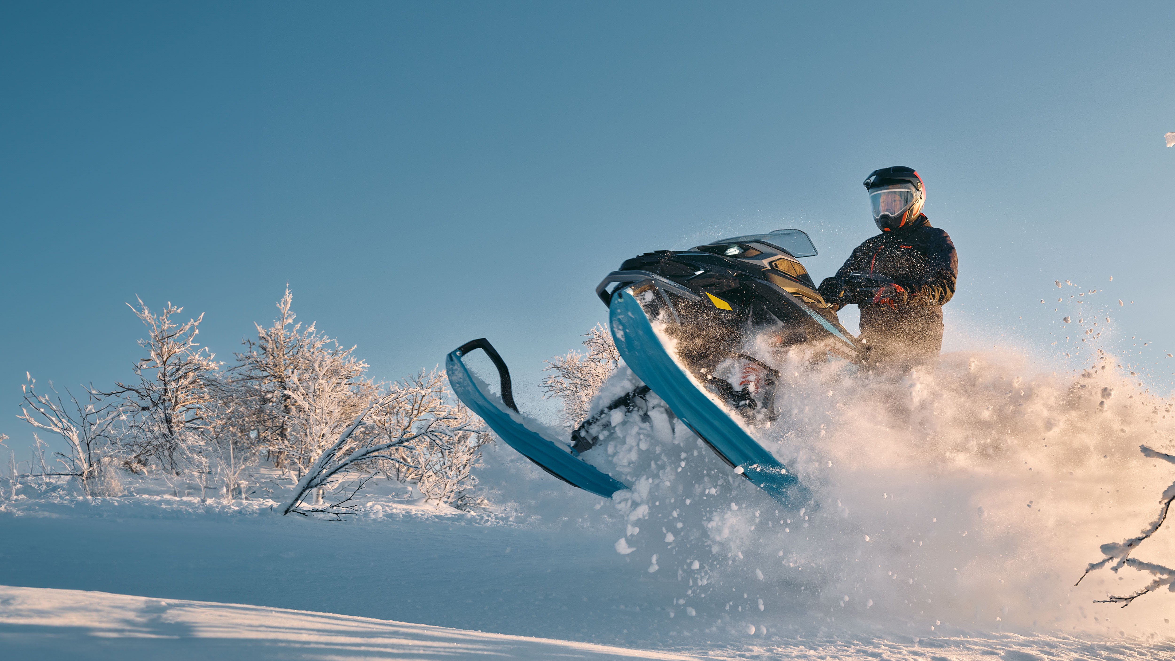 Snowmobiler on 2026 Lynx Commander snowmobile making a jump in a snow-covered forest.