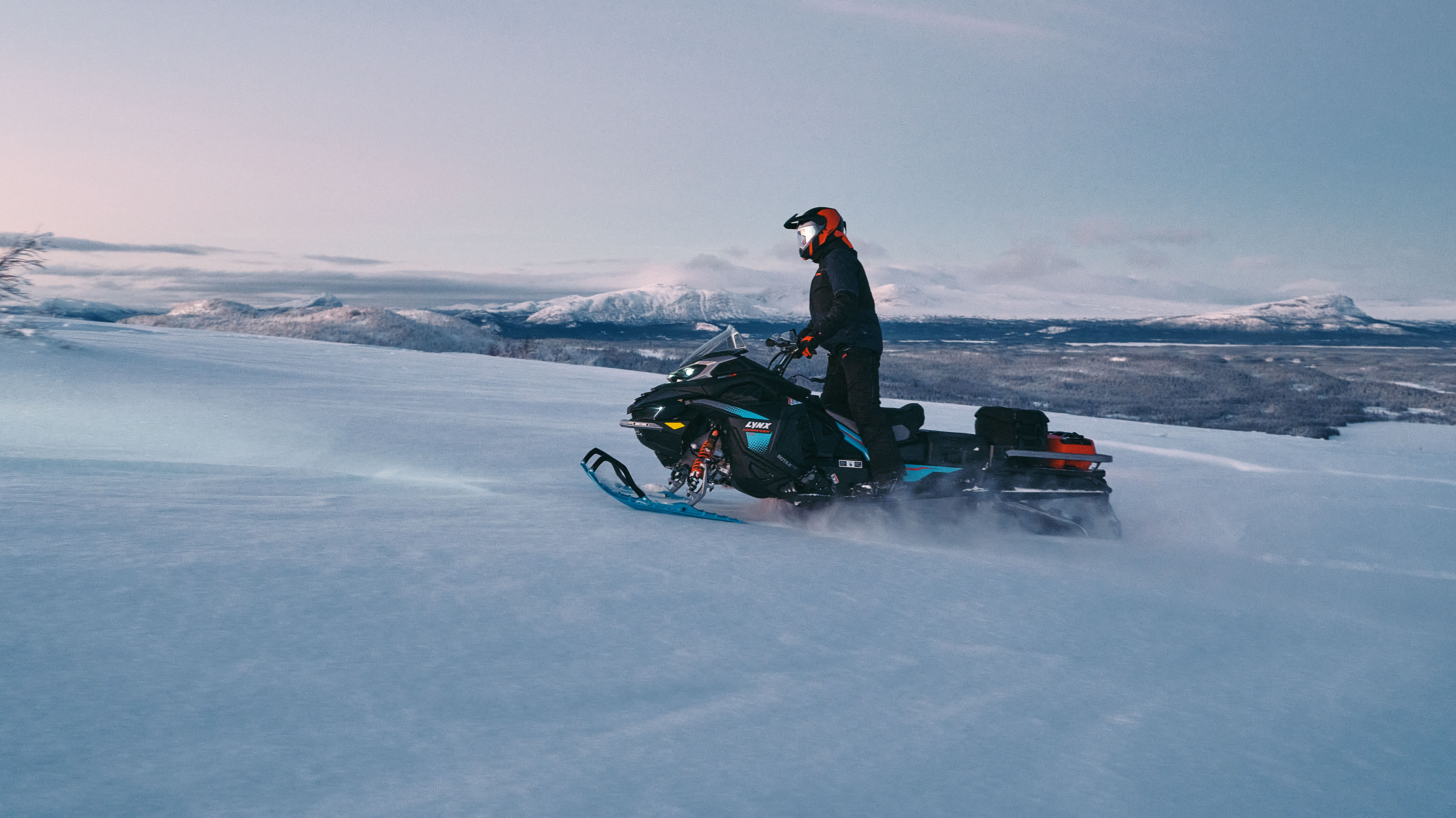 2026 Lynx Commander RE snowmobile riding to the top of a snow-covered mountain.