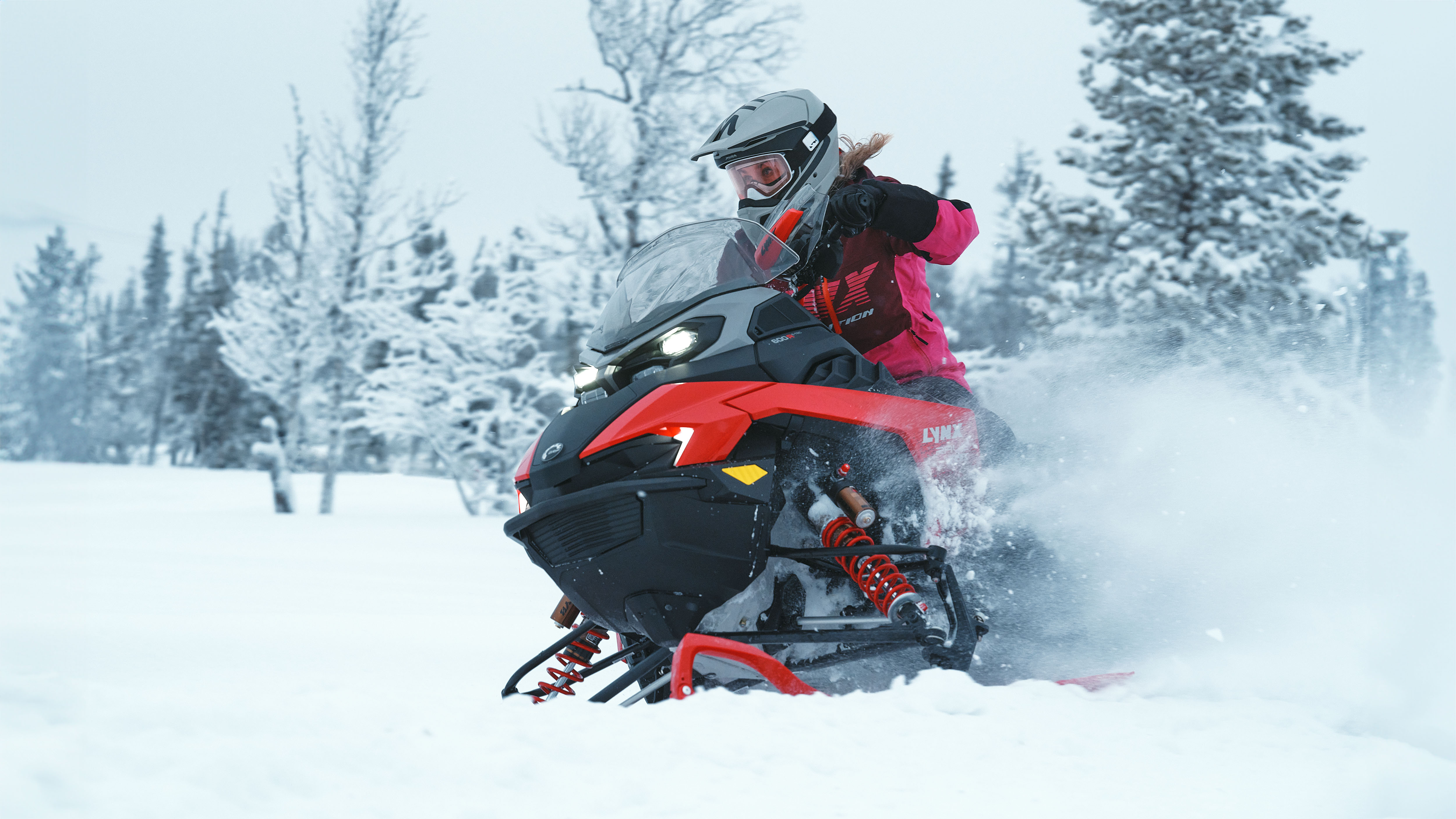 Motoneigiste conduisant une motoneige Lynx Rave RE 2026 dans la poudreuse fraîche d'une forêt enneigée.