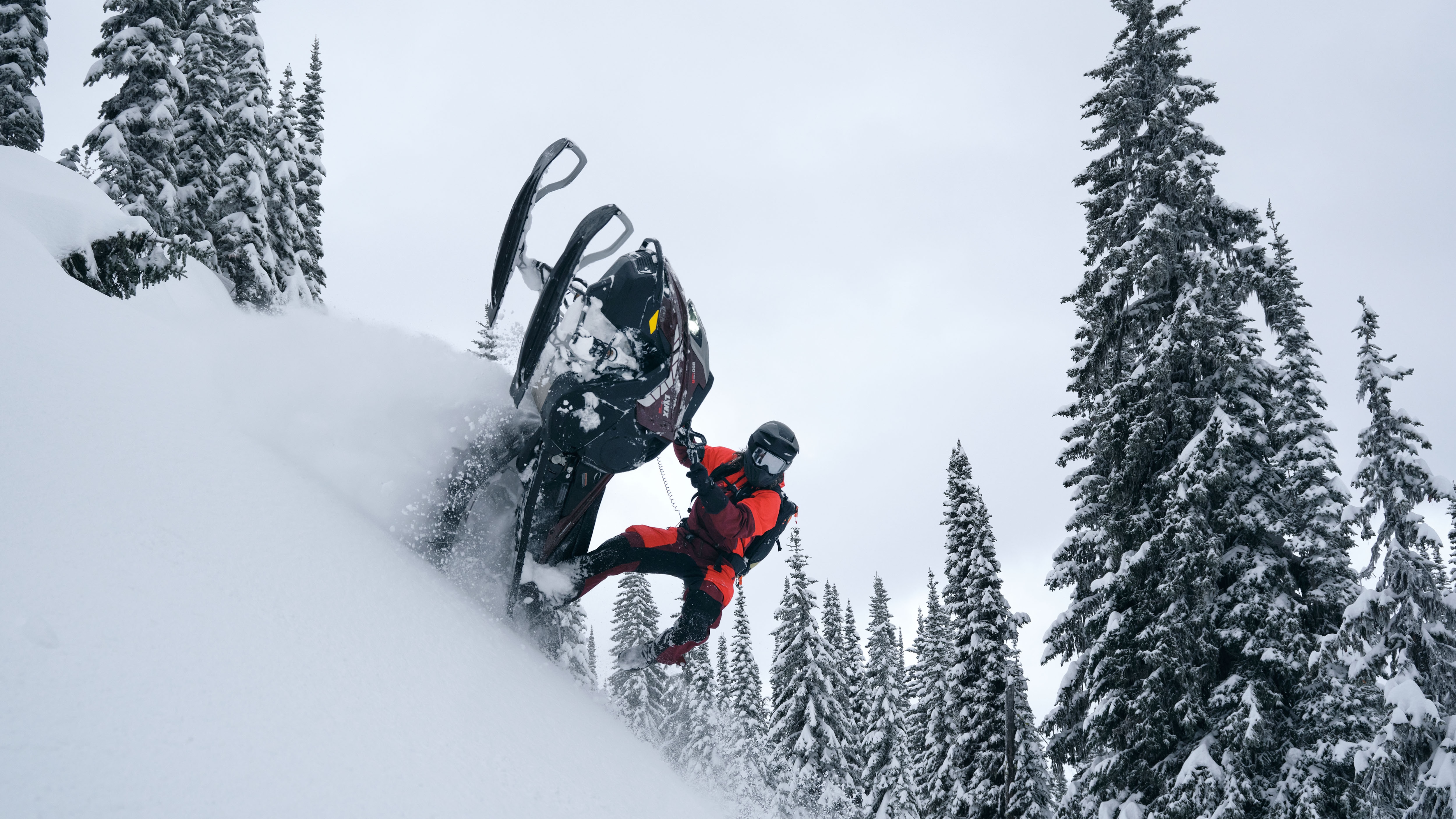 Rider performing a stunt on a Lynx Shredder 2026 snowmobile in a snowy forest.