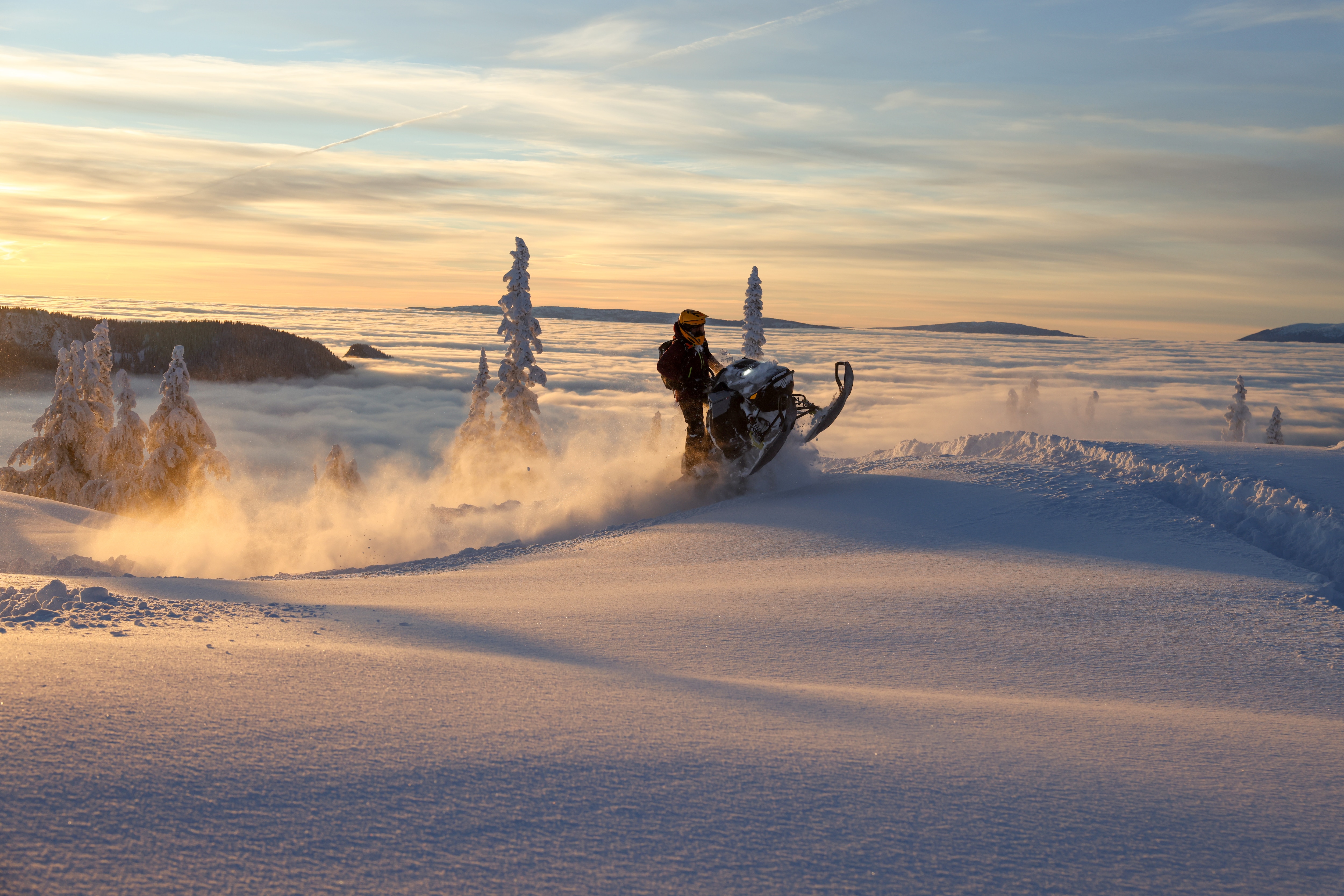 A snowmobiler experiencing the thrill of a Lynx snowmobile riding on a snowy mountain.