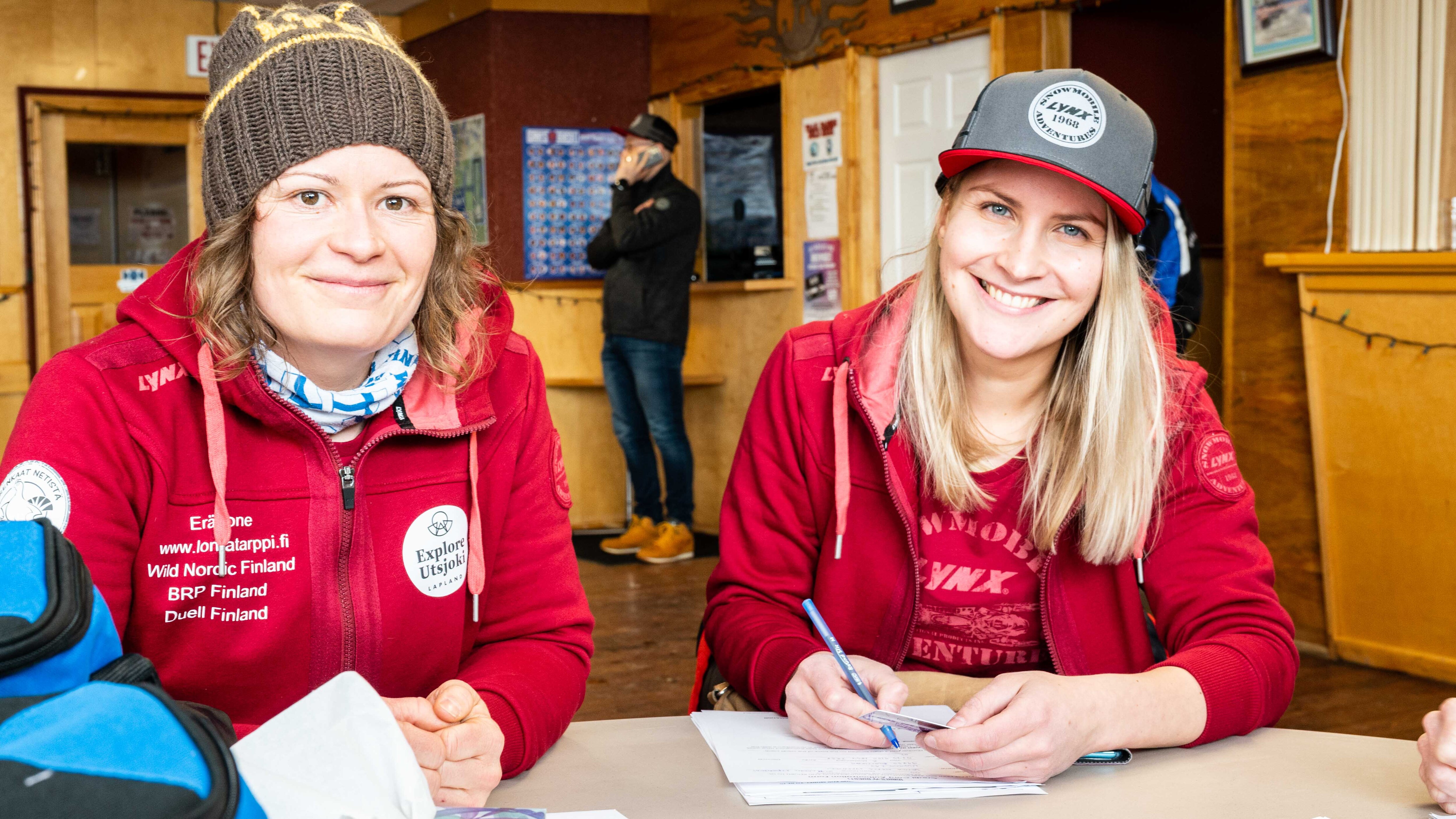 To finske damer smiler og signerer dokumenter
