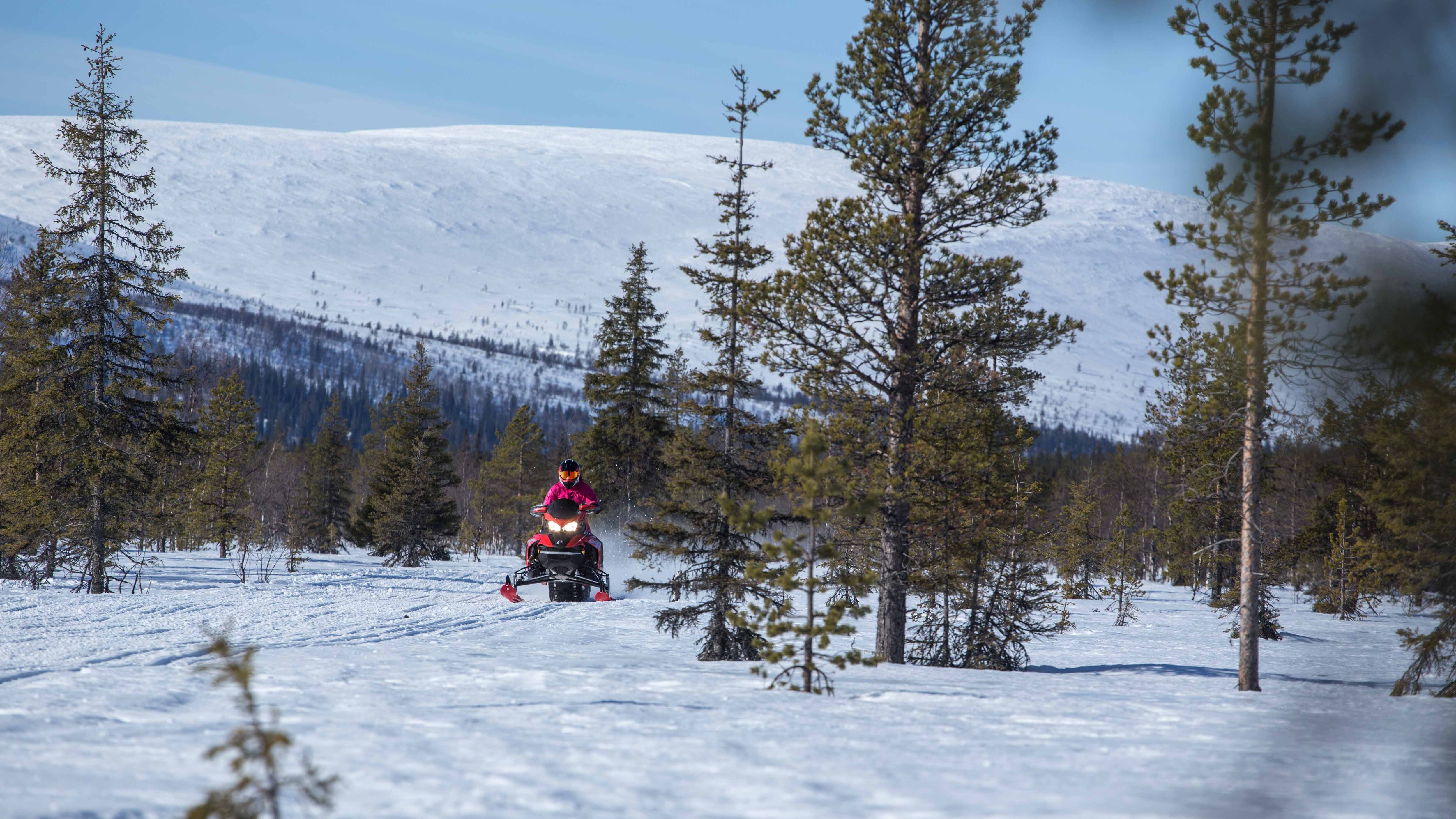 Emma Kimiläinen riding on trail with mountain view in Lapland, Finland with 2022 Lynx Rave RE 850 E-TEC snowmobile