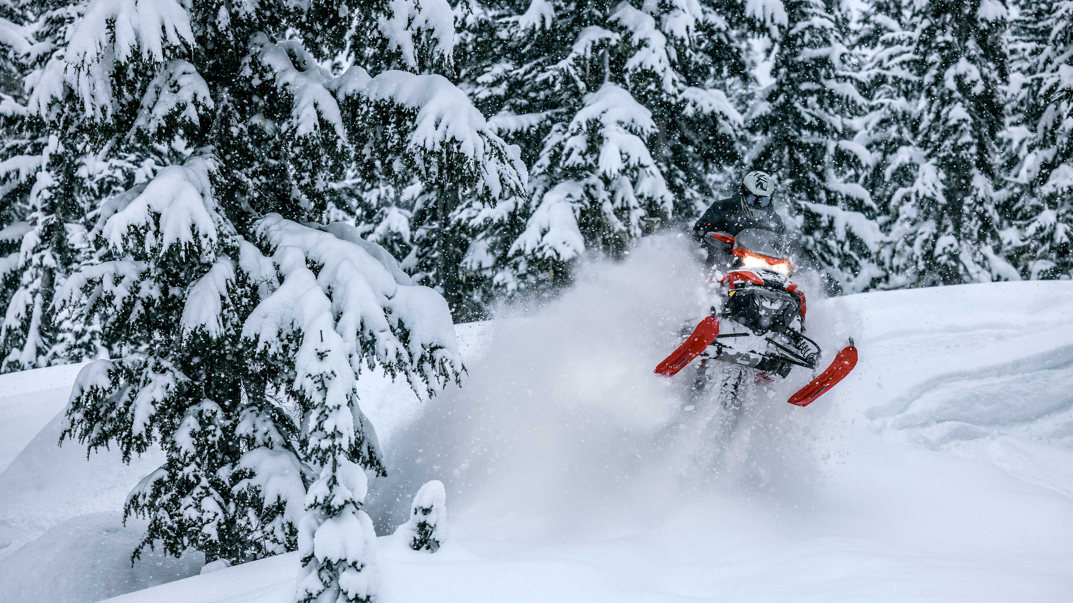 Rider jumping a snowy bump on their 2023 Lynx snowmobile