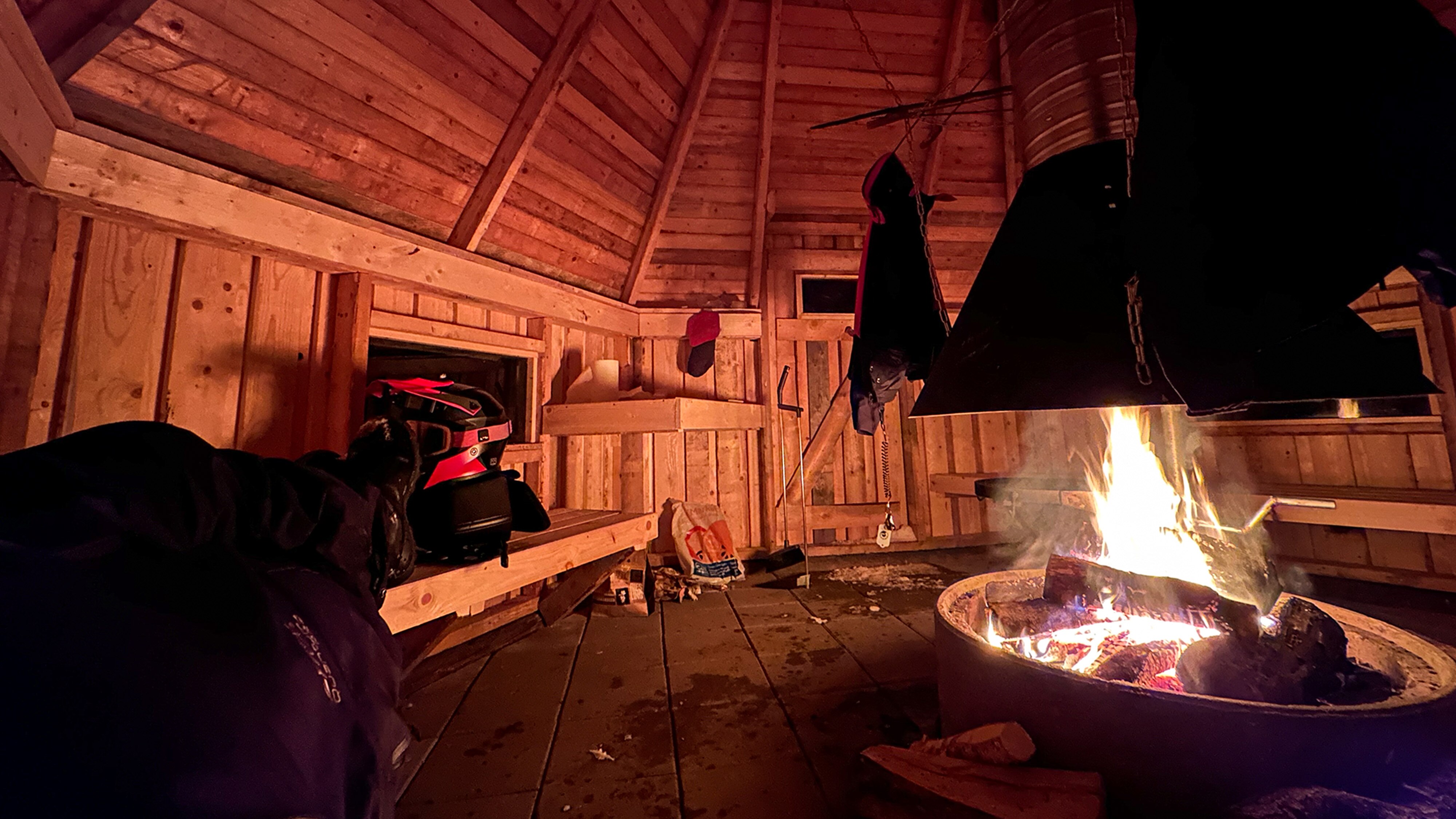 Joni Maununen couché dans un campement avec un feu de camp