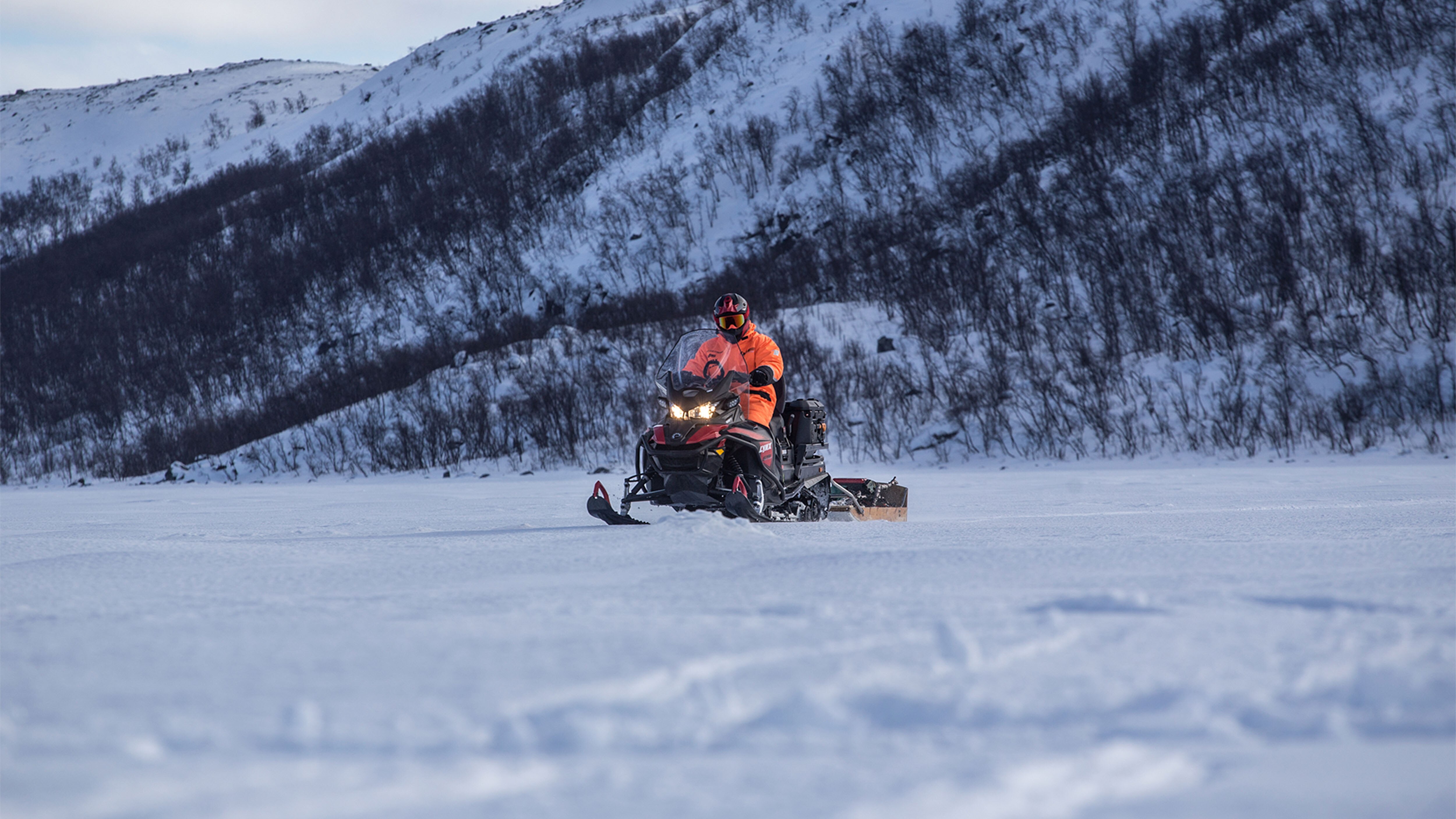 Lynx 59 Ranger snowmobile towing sleigh on lake ice