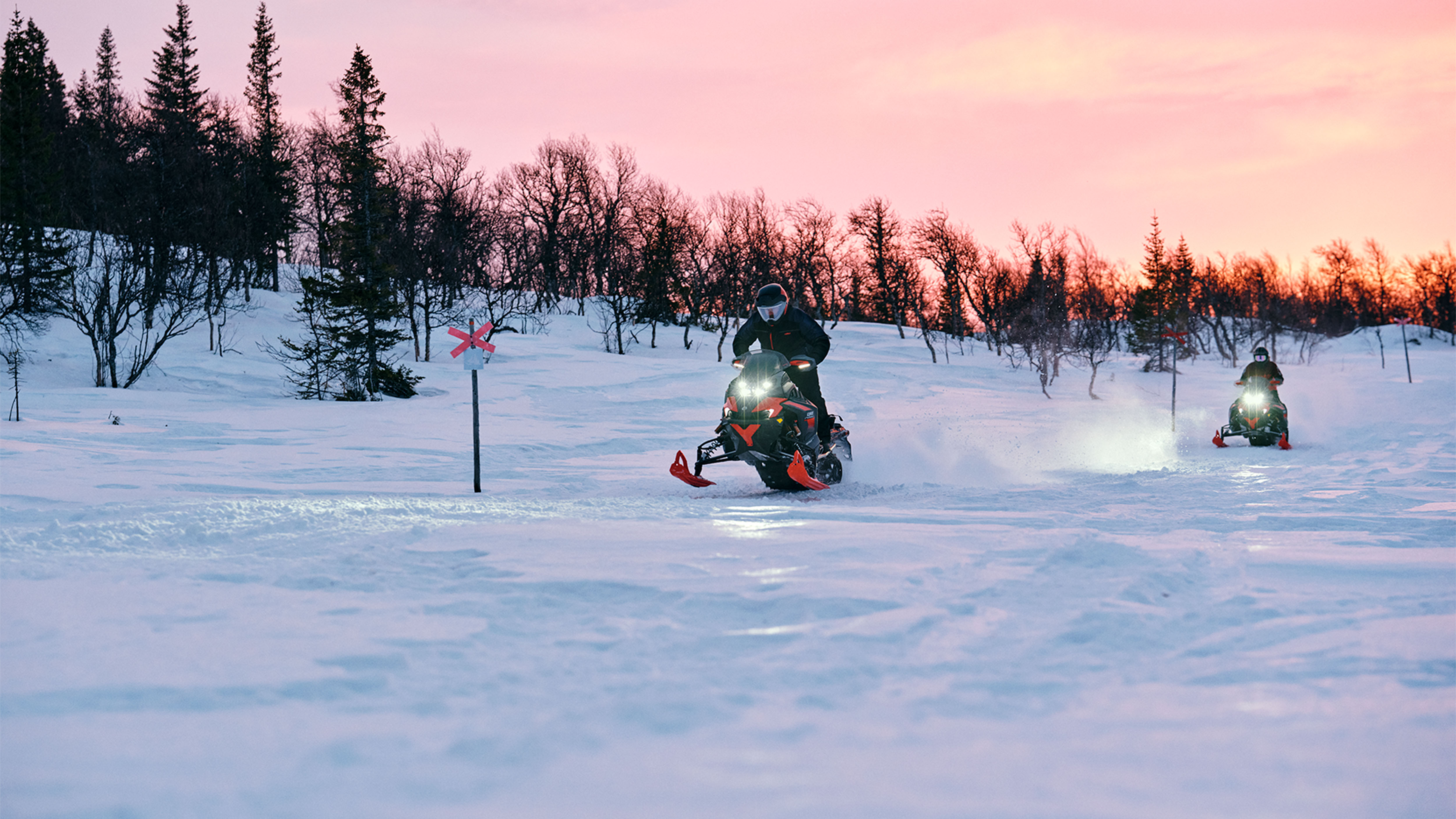 Two Lynx Xterrain RE 2025 snowmobiles riding on trail at sunrise